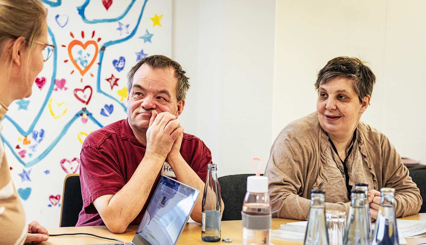 Drei Personen sitzen an einem Tisch und sprechen miteinander