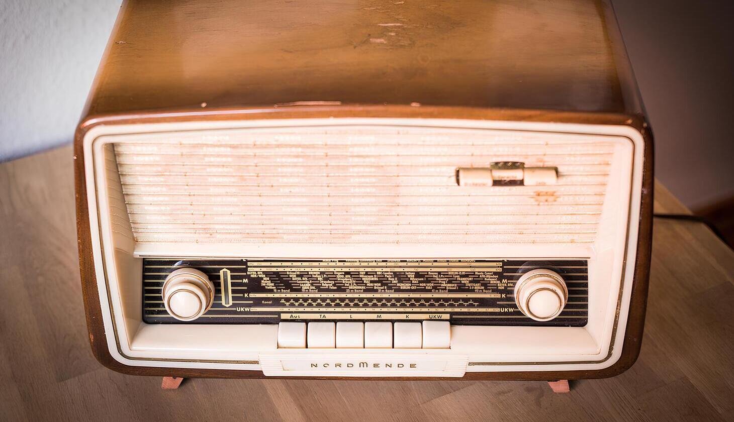 Altes Nordmende-Radio im Holzgehäuse mit cremefarbener Front, zwei großen Drehknöpfen, Skalenanzeige und mehreren Tasten an der Unterseite.